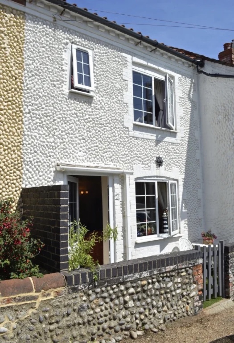 The flint and brick front of Splashpoint cottage on a sunny day